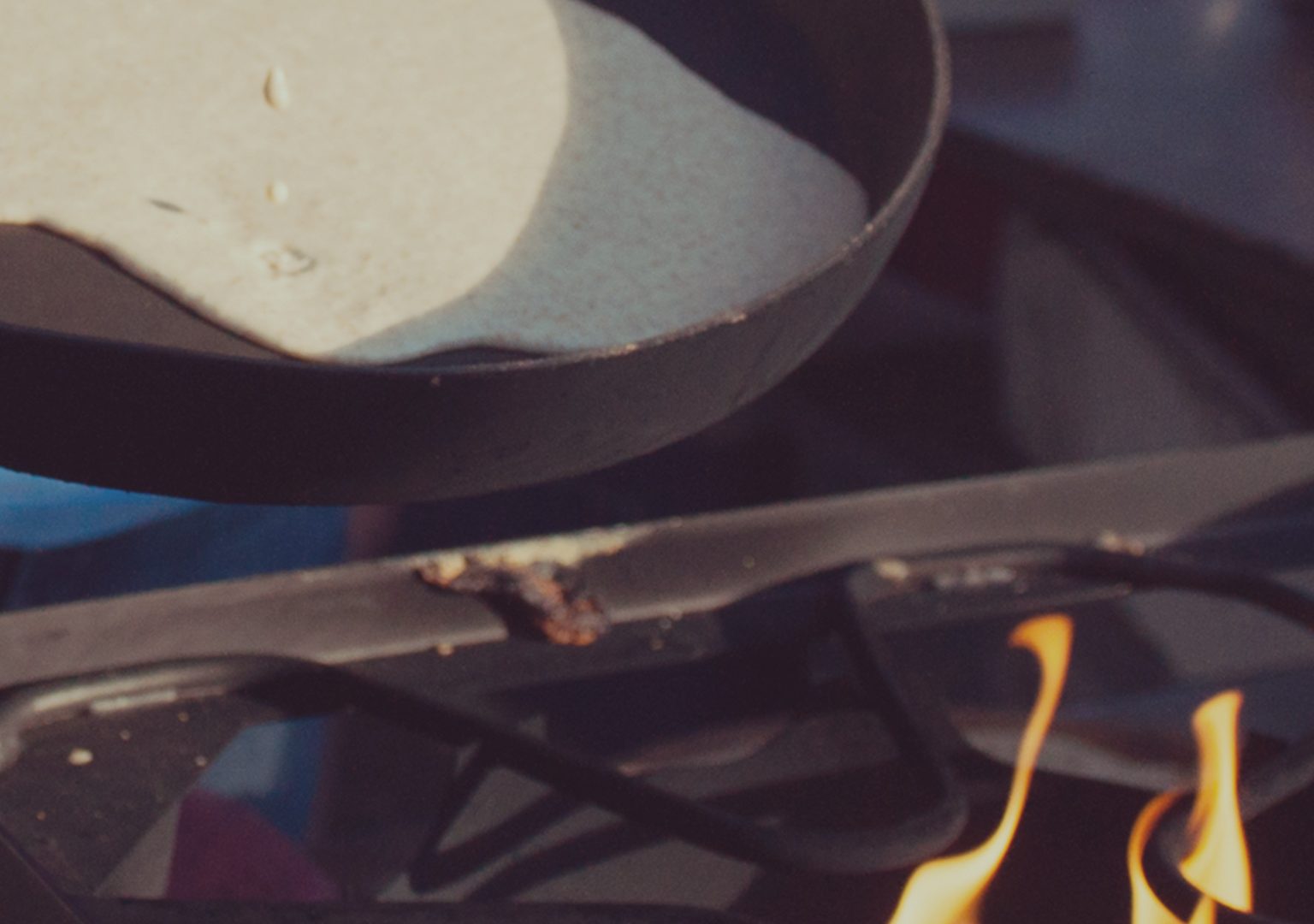 Close-up of festival worker pouring pancake batter into skillet over open flame