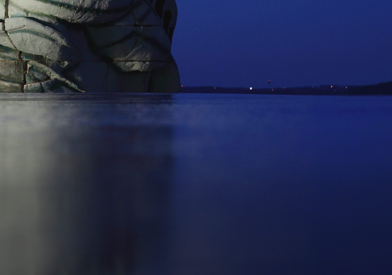 Replica of the top of the head of Statue of Liberty sits atop a frozen lake at night